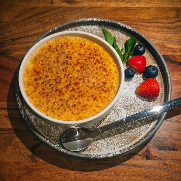 Crème brûlée mit karamellisierter Zuckerkruste, frischen Beeren und Minze